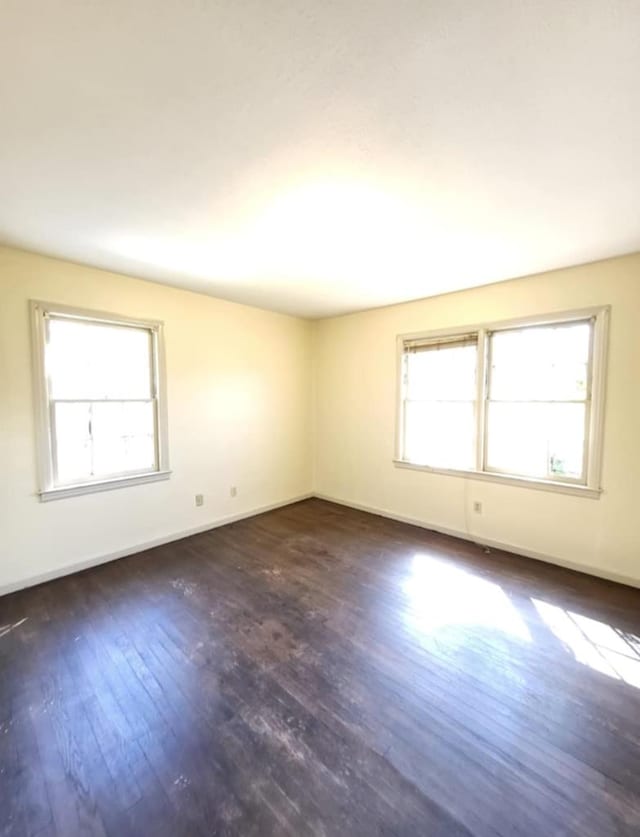 empty room featuring baseboards and dark wood-style flooring