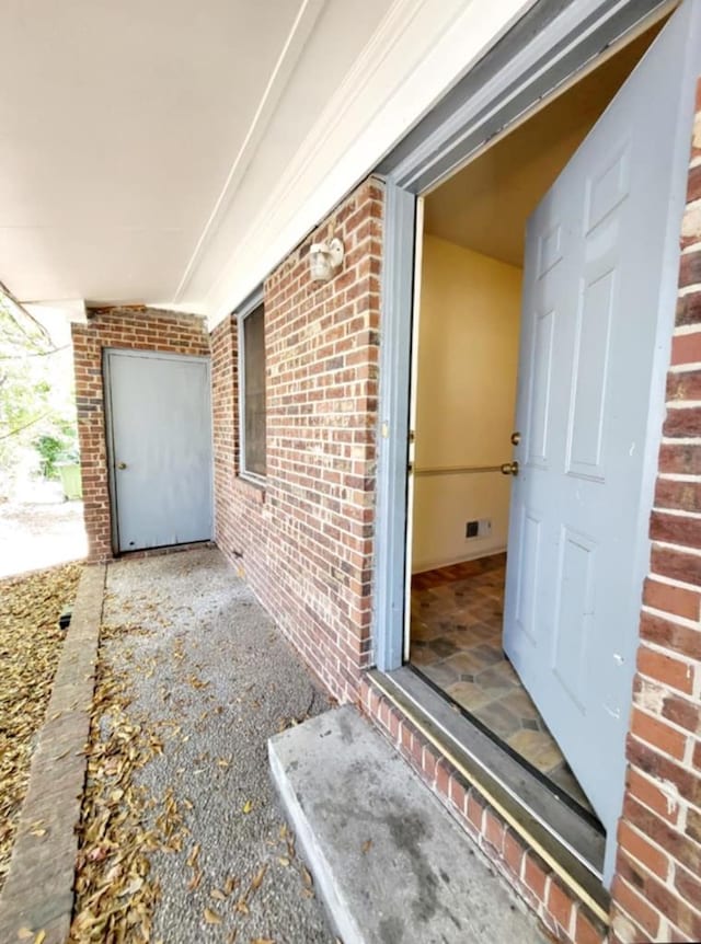 view of exterior entry featuring brick siding