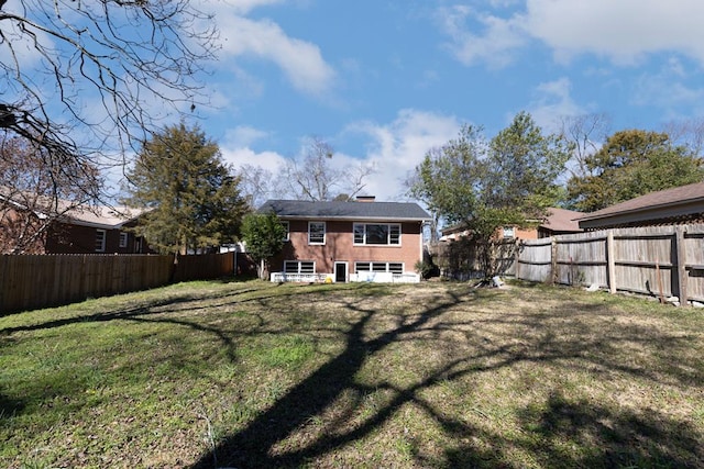 rear view of property with a fenced backyard and a lawn