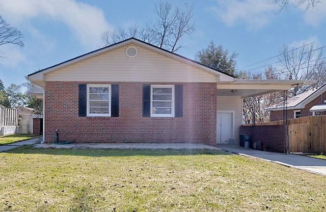 view of front of house featuring brick siding, a front lawn, fence, and an attached carport