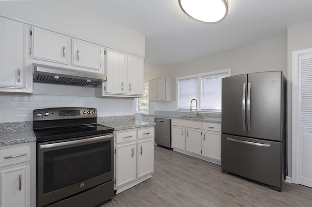 kitchen with white cabinets, under cabinet range hood, stainless steel appliances, and a sink