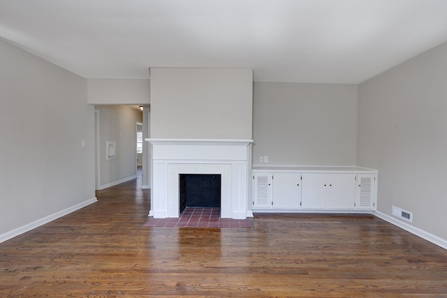 unfurnished living room with dark wood-type flooring, a fireplace with flush hearth, visible vents, and baseboards