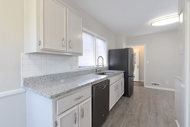 kitchen featuring visible vents, dishwasher, freestanding refrigerator, white cabinetry, and a sink