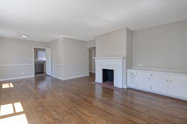 unfurnished living room with a fireplace with flush hearth, dark wood-type flooring, and baseboards