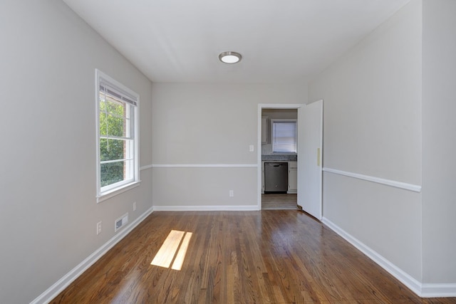 empty room featuring baseboards, visible vents, and dark wood-style flooring