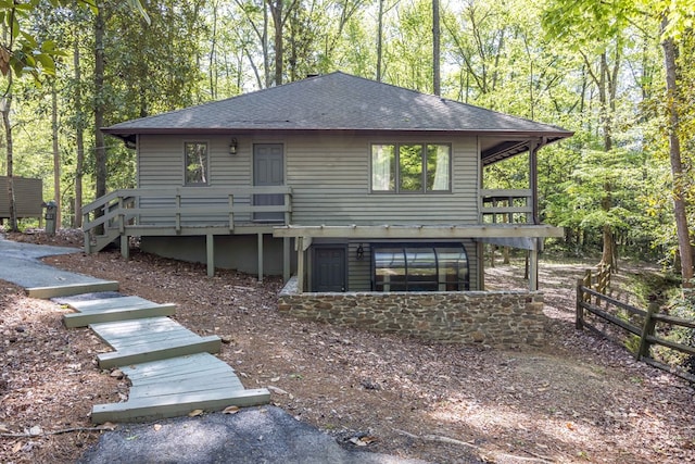 back of property featuring a wooden deck, roof with shingles, stairway, and fence