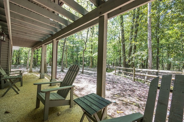 view of patio featuring a view of trees and fence
