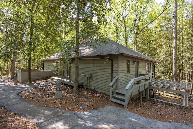 view of home's exterior featuring a view of trees and a shingled roof