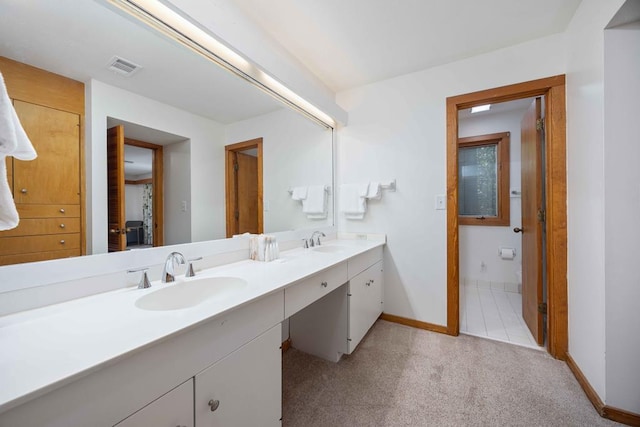 bathroom with baseboards, visible vents, a sink, and double vanity
