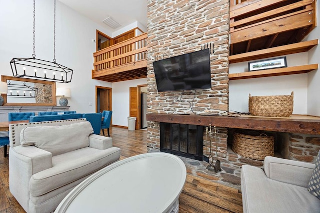 living area featuring a towering ceiling, baseboards, wood finished floors, and a fireplace