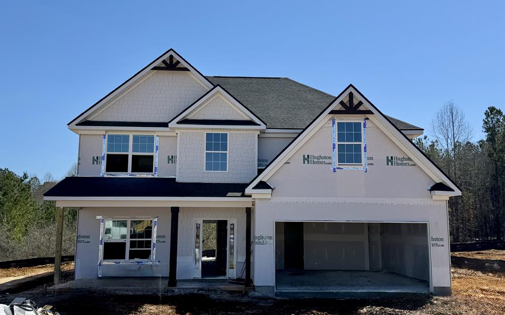 property in mid-construction featuring covered porch, a garage, and driveway