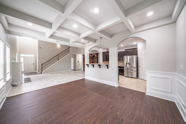 7312 Sorrel Ct, Columbus, GA 31909 - unfurnished living room featuring light wood-style flooring, beam ceiling, coffered ceiling, arched walkways, and recessed lighting