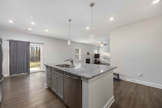 kitchen with ceiling fan, dishwasher, hanging light fixtures, light stone countertops, and sink