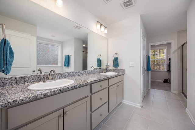 bathroom with an enclosed shower, vanity, and tile patterned flooring