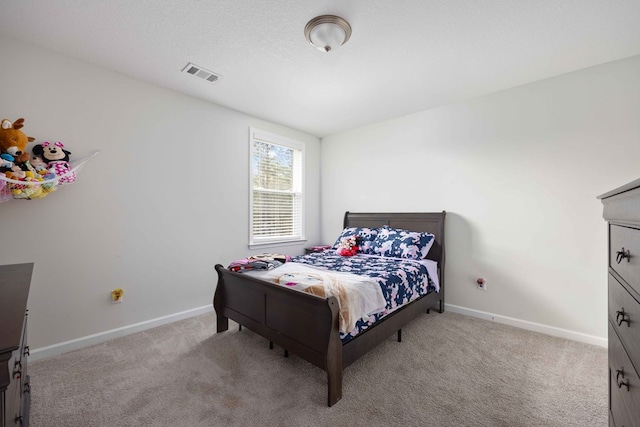 bedroom with light colored carpet and a textured ceiling