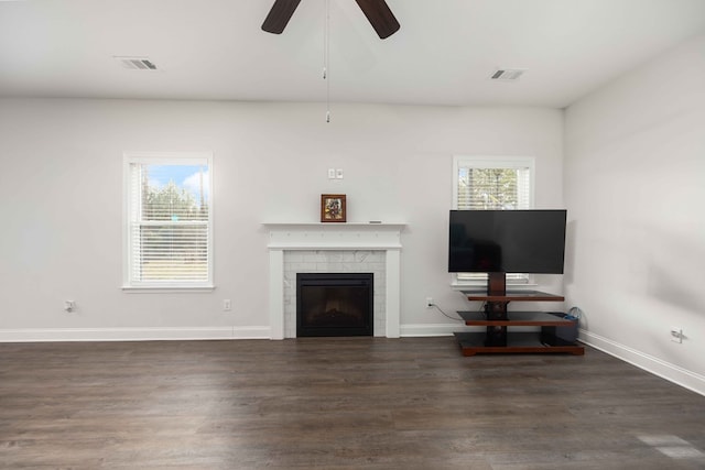 unfurnished living room featuring ceiling fan, dark hardwood / wood-style flooring, and a tiled fireplace