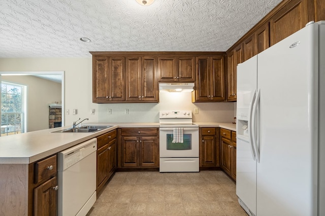 kitchen with a textured ceiling, sink, white appliances, and kitchen peninsula