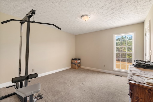 workout room featuring light colored carpet and a textured ceiling