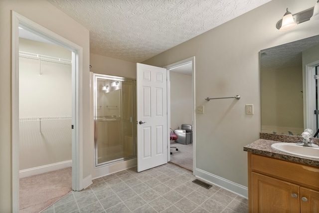 bathroom featuring vanity, a shower with shower door, and a textured ceiling