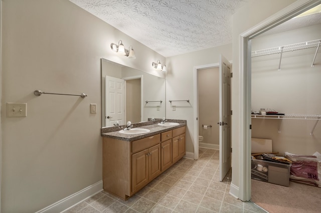 bathroom with vanity, a textured ceiling, and toilet