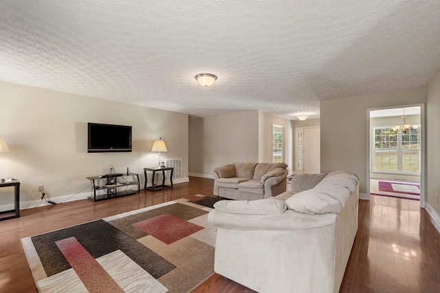 living room featuring a chandelier, dark wood-type flooring, and a textured ceiling