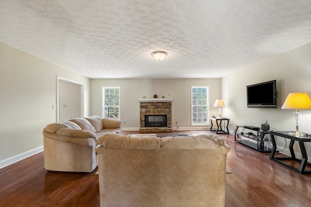 living room featuring a textured ceiling, dark hardwood / wood-style floors, and a stone fireplace