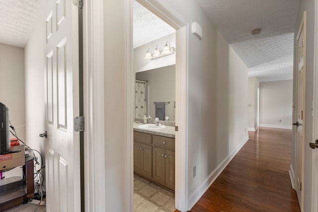 corridor featuring a textured ceiling, light hardwood / wood-style floors, and sink