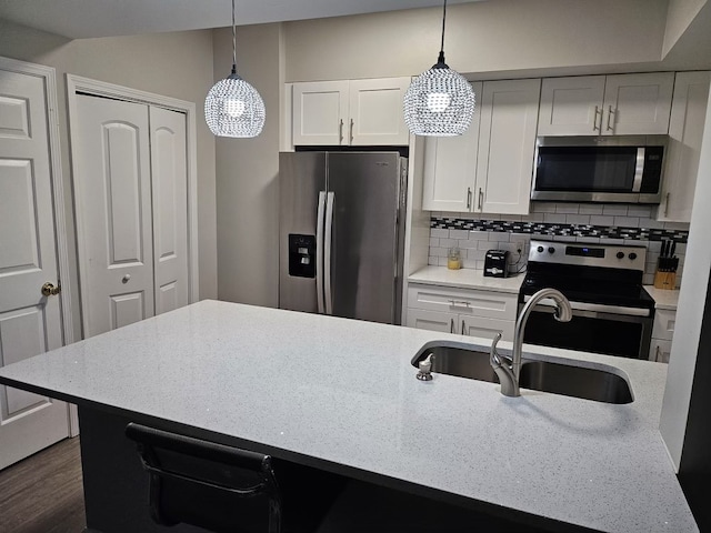 kitchen featuring white cabinets, appliances with stainless steel finishes, pendant lighting, and sink