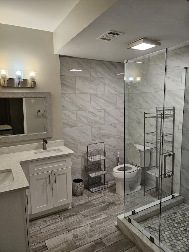 bathroom featuring a shower with door, vanity, and toilet