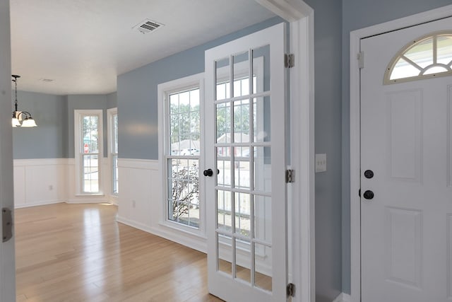 entryway featuring a wainscoted wall, light wood-style floors, and visible vents