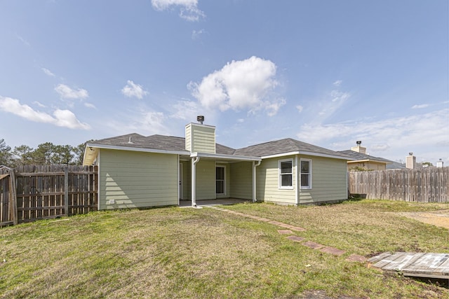 rear view of house featuring a lawn, fence, and a chimney