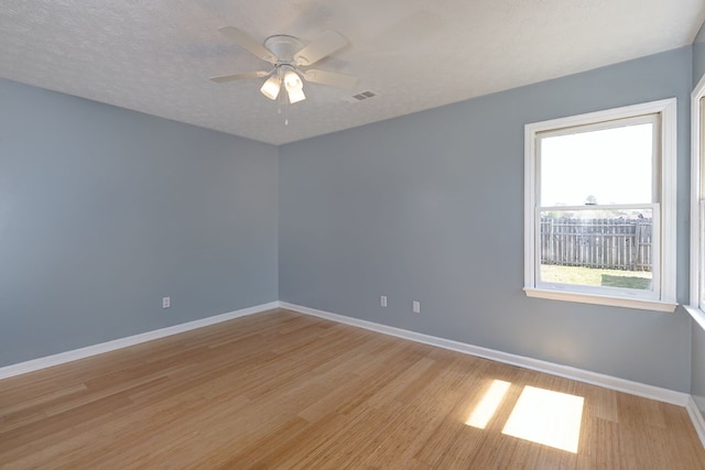 unfurnished room with visible vents, a textured ceiling, baseboards, and a ceiling fan