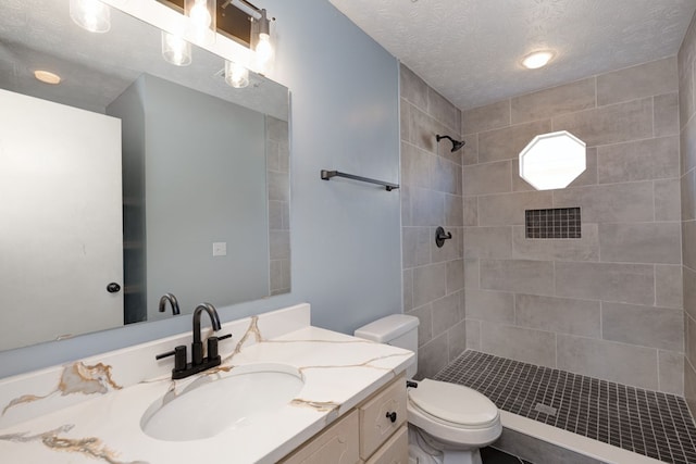 bathroom featuring tiled shower, a textured ceiling, toilet, and vanity