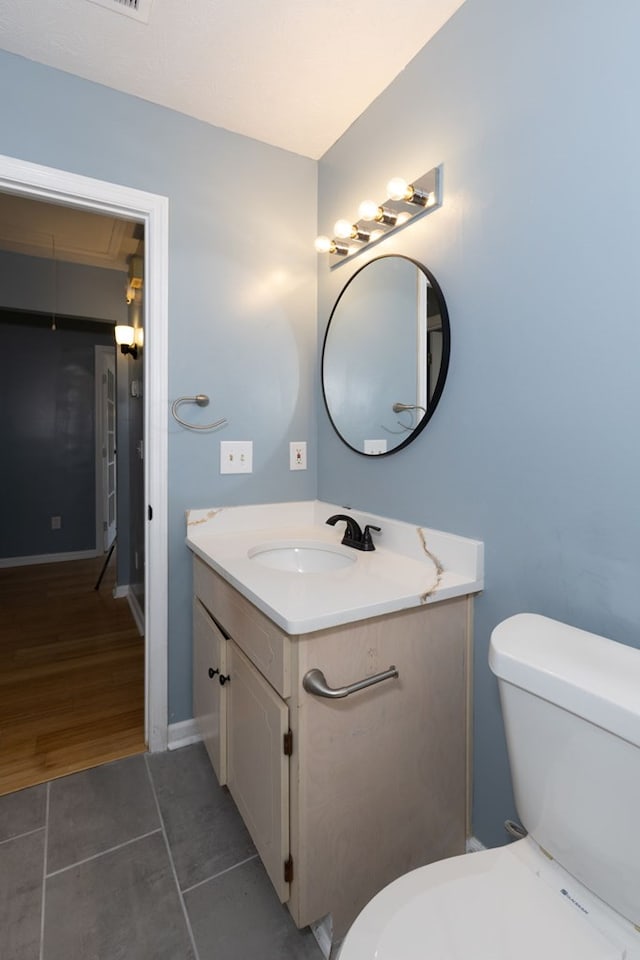 half bathroom with baseboards, toilet, vanity, and tile patterned flooring