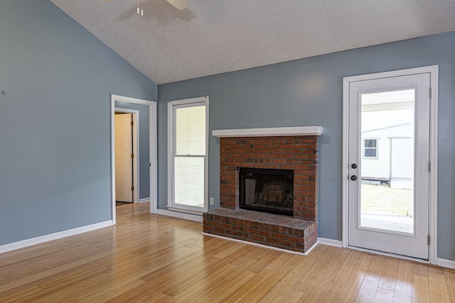 unfurnished living room featuring baseboards, vaulted ceiling, a fireplace, light wood-style floors, and a ceiling fan