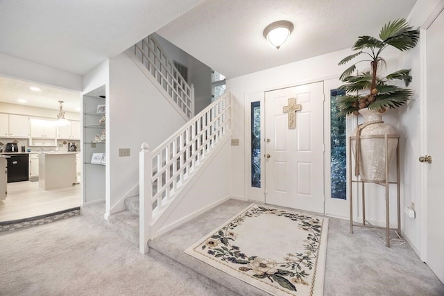 carpeted foyer entrance with a textured ceiling