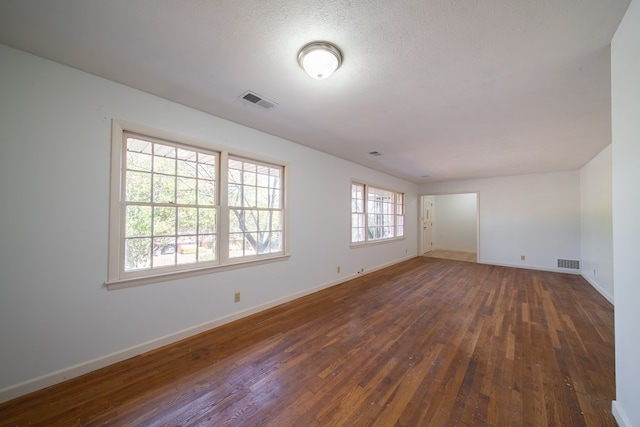 empty room featuring dark wood-type flooring and a textured ceiling