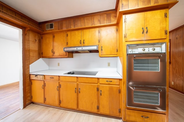 kitchen with black electric cooktop, double oven, and light hardwood / wood-style floors