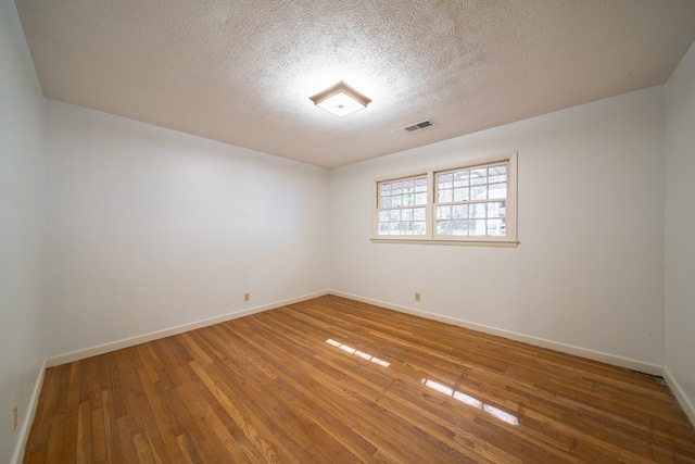 unfurnished room with hardwood / wood-style flooring and a textured ceiling