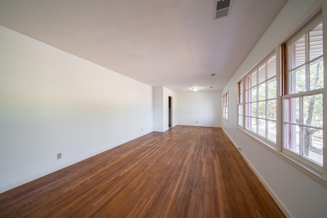 spare room featuring a healthy amount of sunlight and dark hardwood / wood-style floors