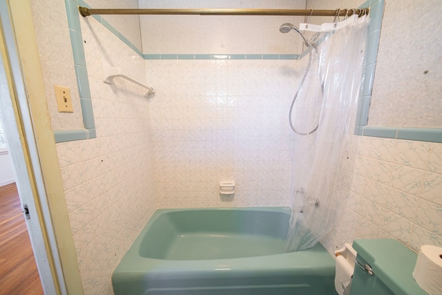 bathroom with shower / bath combo with shower curtain, toilet, hardwood / wood-style floors, and tile walls