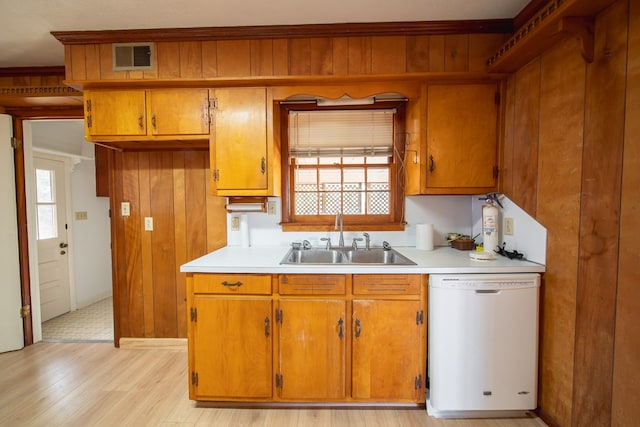 kitchen with sink, wooden walls, and dishwasher