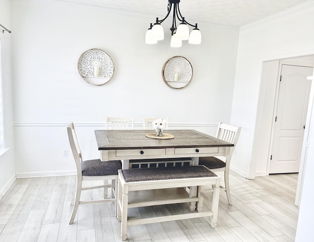 dining space with an inviting chandelier, light wood-style flooring, baseboards, and ornamental molding