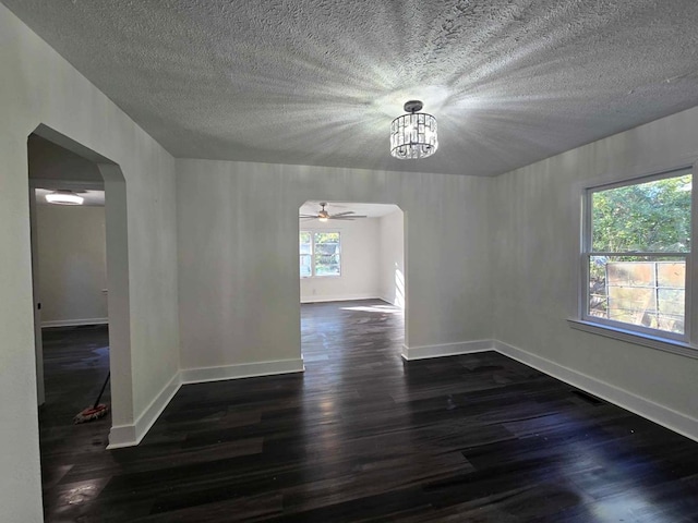 unfurnished room with dark hardwood / wood-style flooring, ceiling fan with notable chandelier, and a textured ceiling