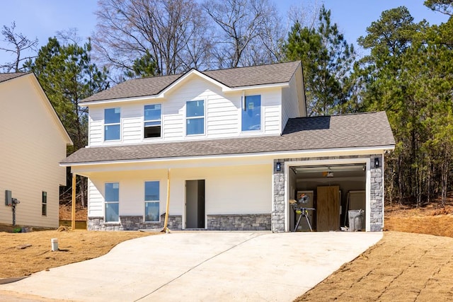 view of front of home with a garage, concrete driveway, roof with shingles, and stone siding