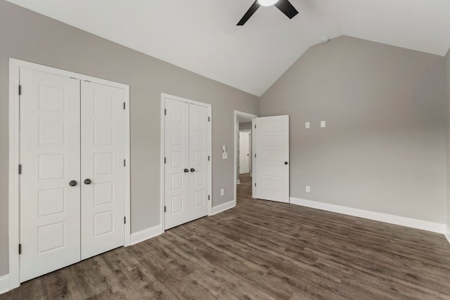 unfurnished bedroom with ceiling fan, multiple closets, dark wood-type flooring, and vaulted ceiling