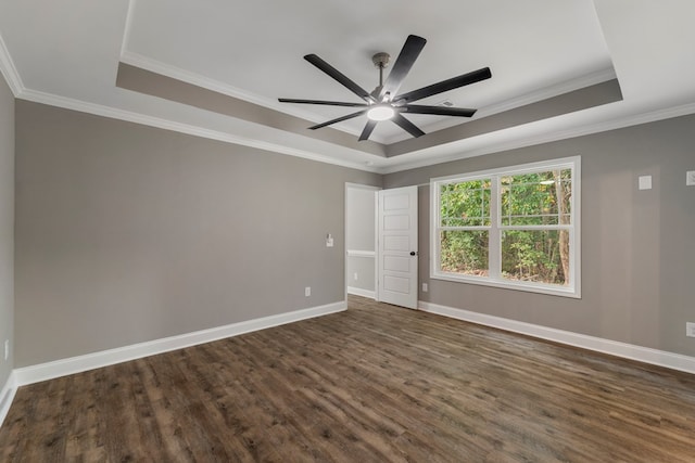 unfurnished room featuring a raised ceiling, ceiling fan, dark hardwood / wood-style floors, and ornamental molding