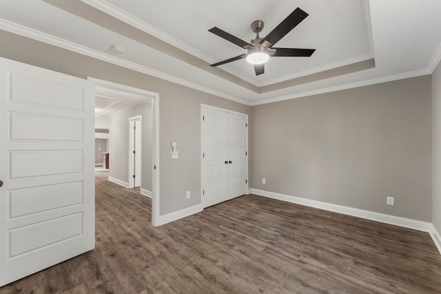 unfurnished bedroom with ceiling fan, dark hardwood / wood-style floors, a raised ceiling, and ornamental molding