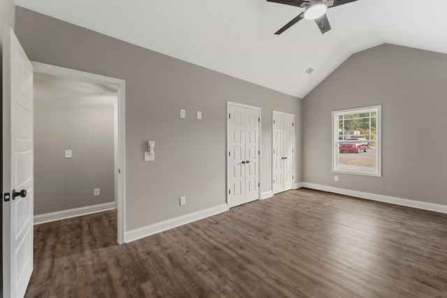 unfurnished bedroom featuring ceiling fan, dark hardwood / wood-style floors, lofted ceiling, and two closets