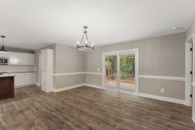 unfurnished dining area with dark wood-type flooring and a notable chandelier